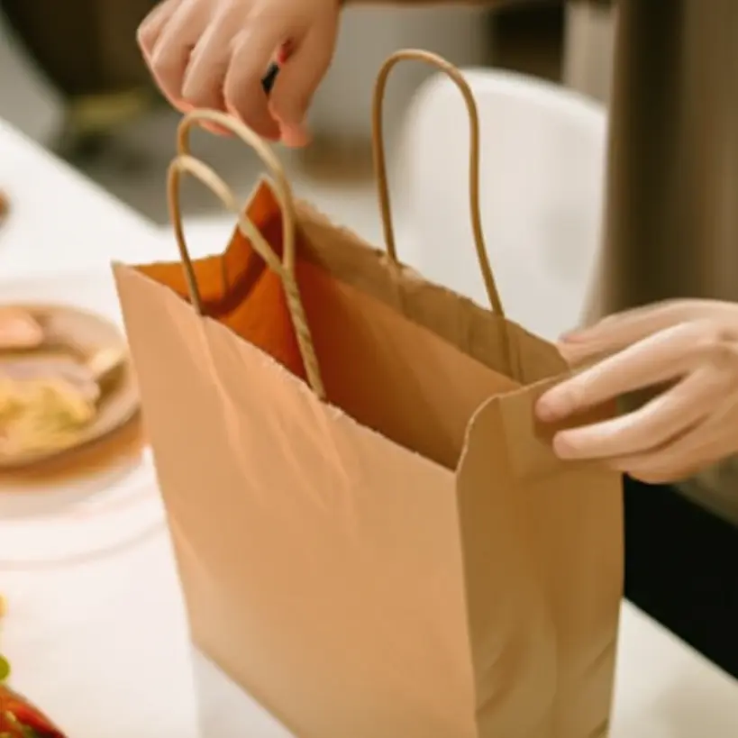 Mãos de cliente abrindo saco kraft com comida delivery, unboxing
