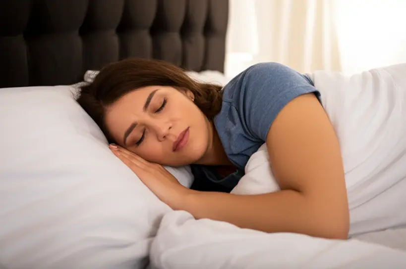 Uma pessoa dormindo profundamente e tranquilamente em uma cama confortável, com a iluminação suave de um quarto, simbolizando a importância do sono de qualidade para a saúde e prevenção da obesidade.