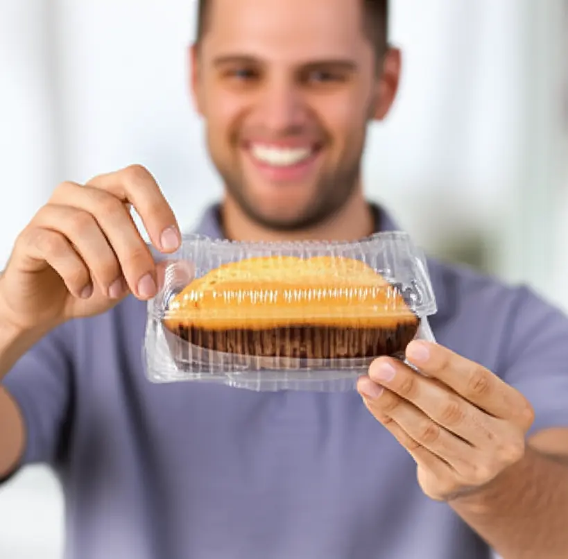 Uma cliente sorridente abrindo uma embalagem transparente que revela um bolo caseirinho fresco e apetitoso, com foco na satisfação e na qualidade do produto.